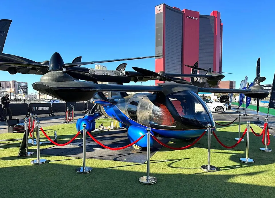 Black and blue ASKA A5 drive-and-fly prototype with wings and rotors deployed, behind a rope barrier outdoors