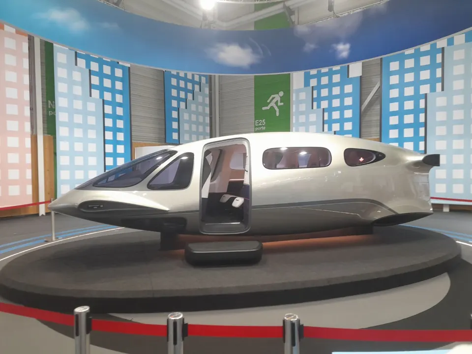 Silver-green Lilium Jet full-scale cabin mock-up with an open door on a round display platform